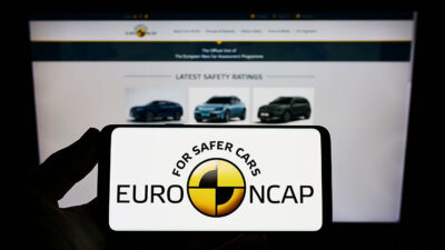 Stuttgart, Germany - 10-18-2022: Person holding smartphone with logo of car safety programme Euro NCAP on screen in front of website. Focus on phone display. Unmodified photo.