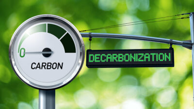 Gauge with inscription CARBON and sign board with text DECARBONIZATION. Concept of Carbon Neutrality